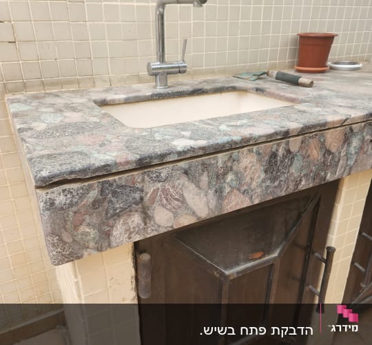 משטח שיש עם כיור וברז מתכת